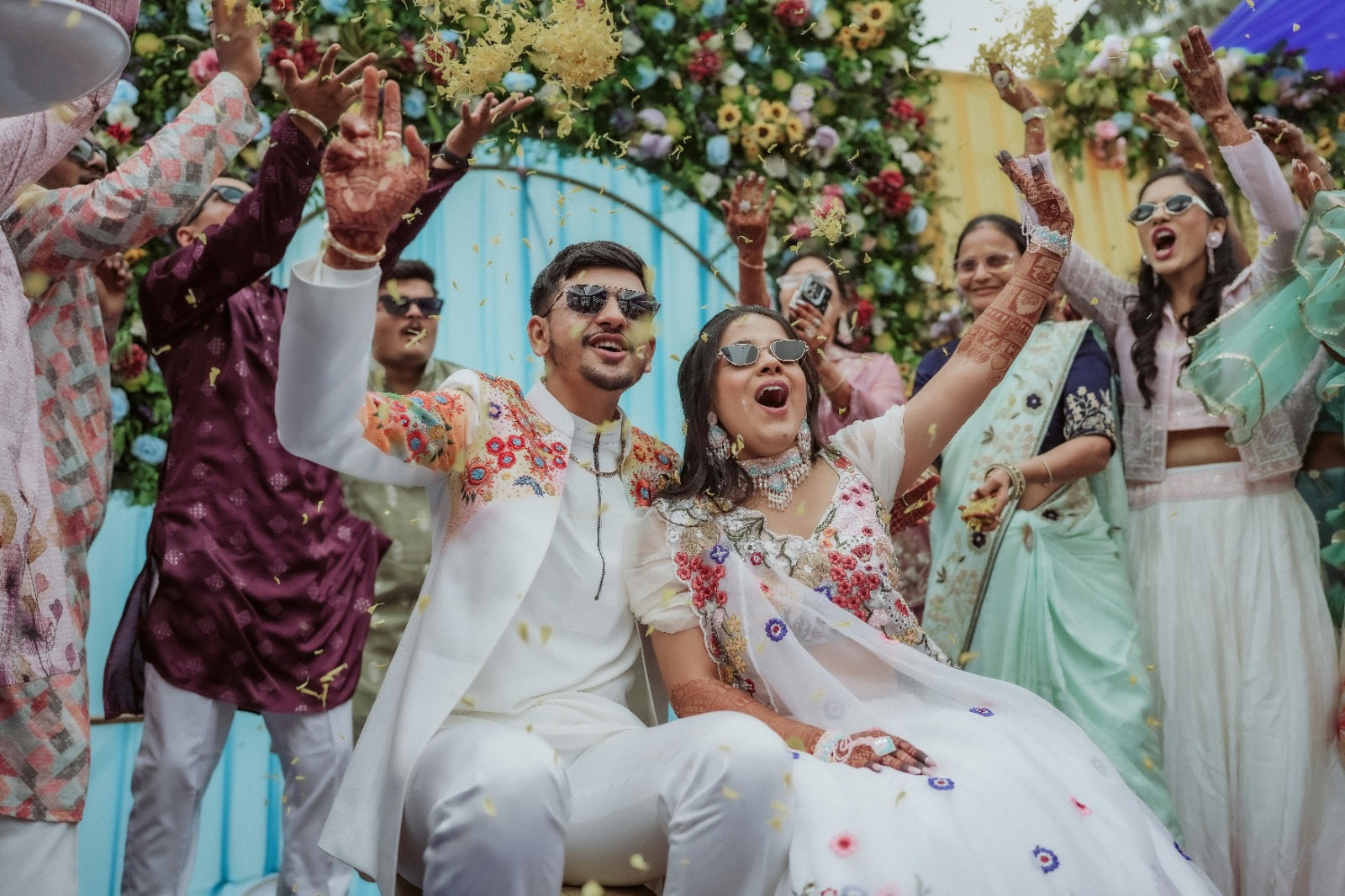Modern Indian wedding with bride in pastel lehenga and groom in ivory sherwani under floral mandap decor.